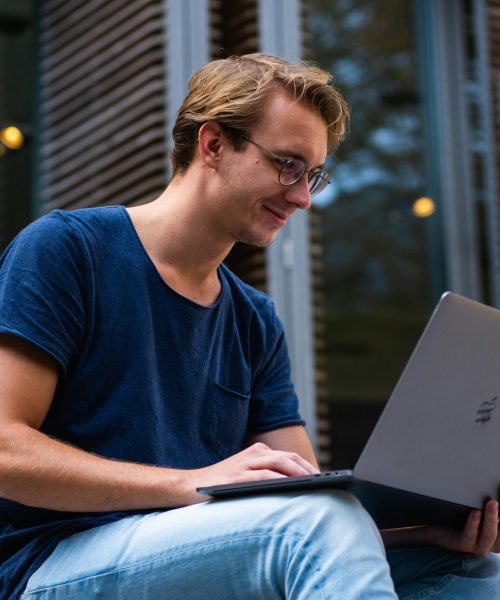 pexels-photo-1438081-1438081 A young man sitting outdoors in Leiden, Netherlands, working on a laptop.
